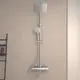 Duschsystem von Ideal Standard mit einer runden Brausestange in Chrom. Die Installation umfasst eine große Kopfbrause und eine Handbrause, montiert an einer hellen Wand.